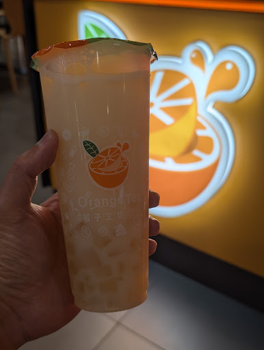 Orange Tea drink in front of the shop sign